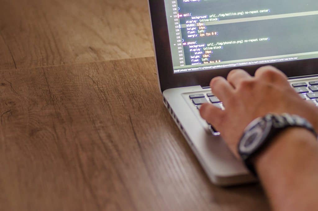 A hand is seen typing on a laptop